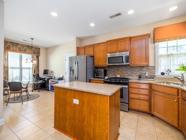 kitchen featuring visible vents, a center island, brown cabinets, appliances with stainless steel finishes, and a sink