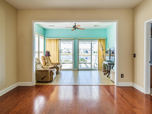 living area featuring a ceiling fan, visible vents, wood finished floors, and baseboards