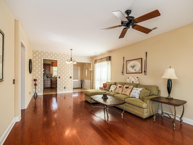 living area with visible vents, wallpapered walls, baseboards, ceiling fan with notable chandelier, and dark wood-style floors