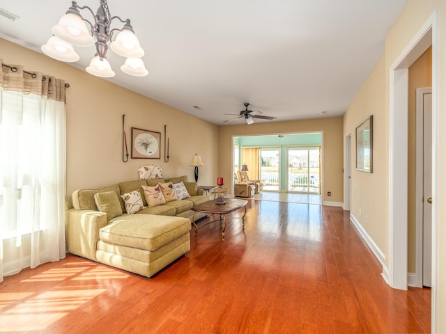 living area with visible vents, ceiling fan with notable chandelier, light wood-type flooring, and baseboards