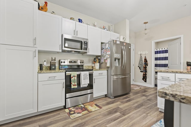 kitchen with light wood-style floors, light stone counters, white cabinets, and stainless steel appliances