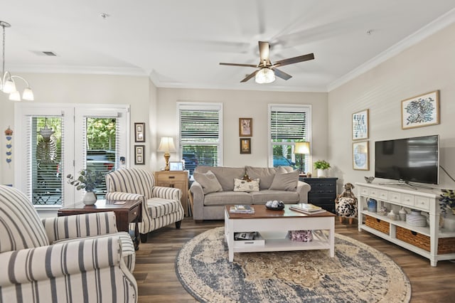 living area with visible vents, ornamental molding, dark wood-style flooring, and ceiling fan with notable chandelier