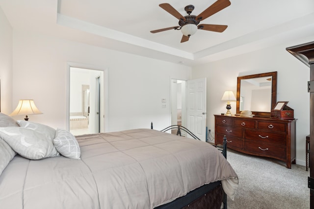 bedroom featuring ceiling fan, a raised ceiling, ensuite bathroom, and light carpet