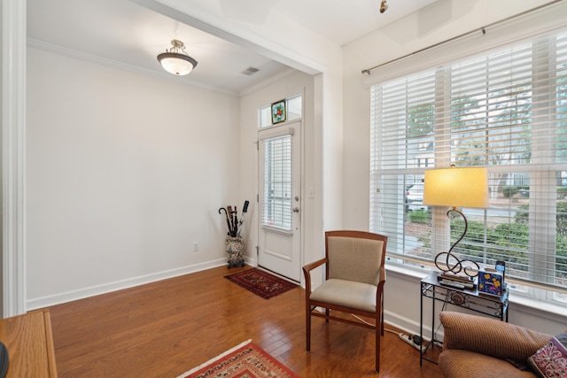 living area with hardwood / wood-style floors and crown molding