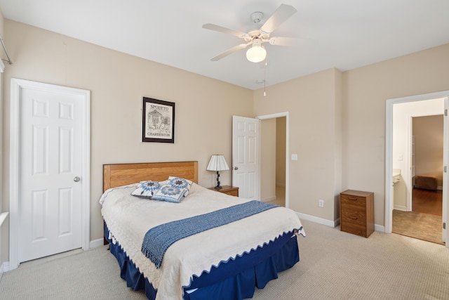 bedroom featuring ceiling fan, ensuite bathroom, and light colored carpet