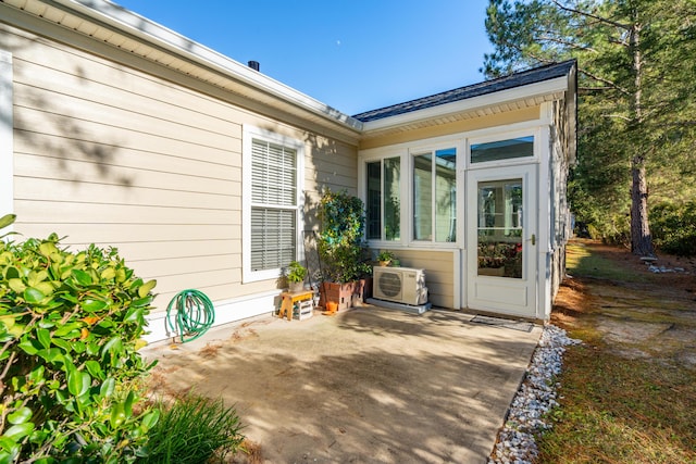 view of exterior entry with ac unit and a patio