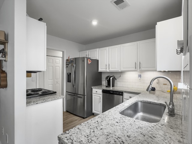 kitchen with white cabinetry, sink, light stone counters, and stainless steel appliances