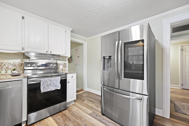 kitchen with backsplash, ornamental molding, stainless steel appliances, light hardwood / wood-style flooring, and white cabinets