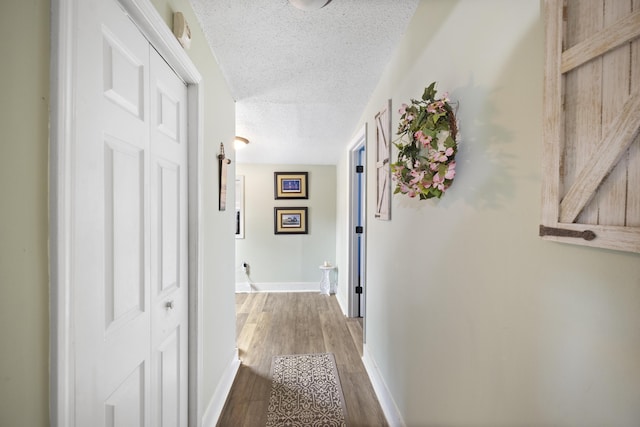 corridor with a textured ceiling and hardwood / wood-style flooring