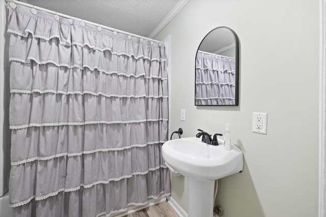 bathroom with hardwood / wood-style floors, a textured ceiling, and crown molding