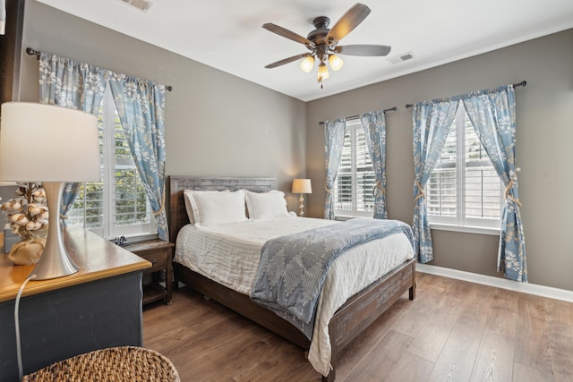 bedroom with multiple windows, wood-type flooring, and ceiling fan