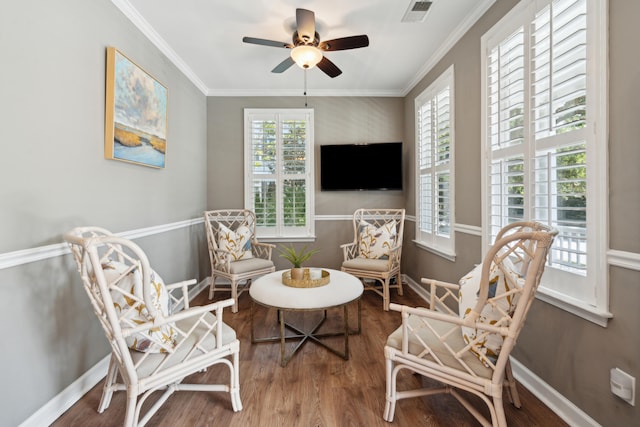 living area with ceiling fan, hardwood / wood-style flooring, plenty of natural light, and ornamental molding