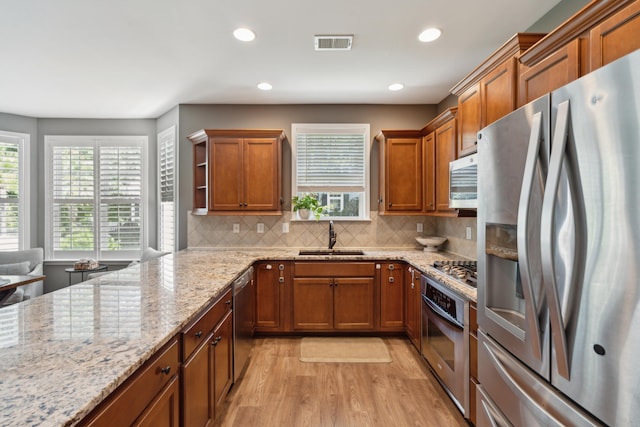 kitchen featuring a healthy amount of sunlight, sink, light hardwood / wood-style flooring, and appliances with stainless steel finishes