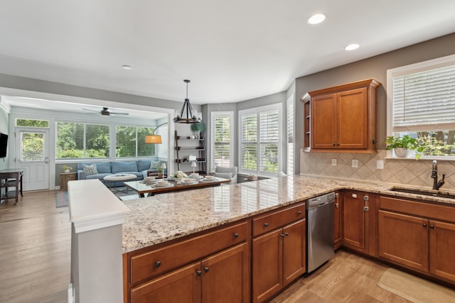 kitchen featuring plenty of natural light, stainless steel dishwasher, sink, and light hardwood / wood-style floors