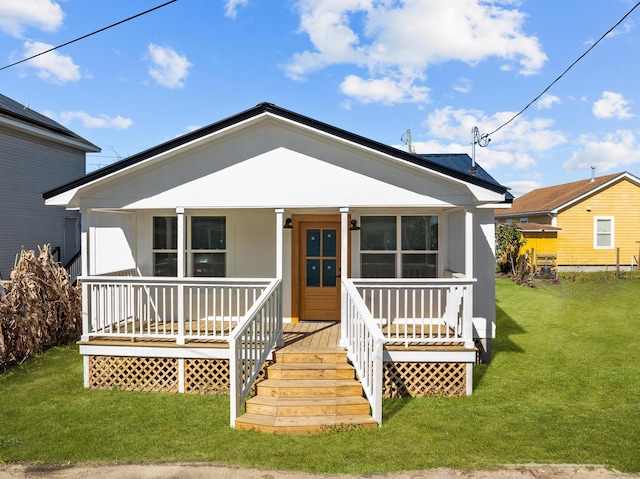 bungalow-style house with a porch, metal roof, and a front lawn