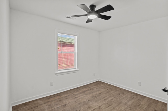 spare room featuring a ceiling fan, visible vents, wood finished floors, and baseboards