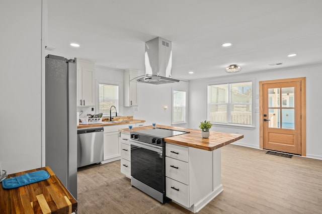 kitchen featuring light wood-style flooring, island exhaust hood, a sink, appliances with stainless steel finishes, and wooden counters