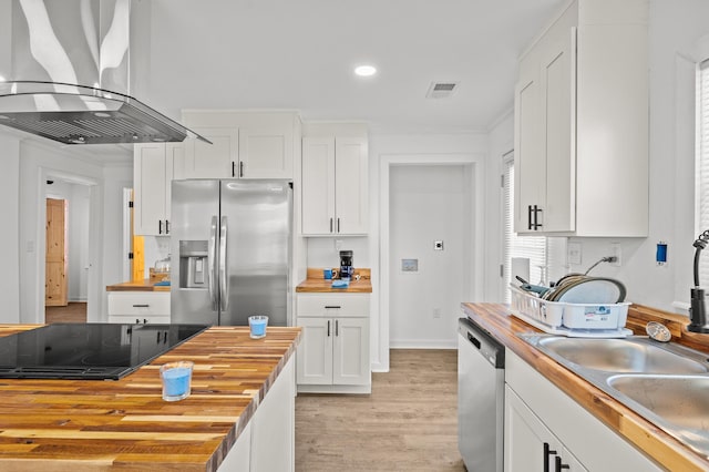 kitchen with visible vents, wooden counters, appliances with stainless steel finishes, white cabinetry, and wall chimney exhaust hood