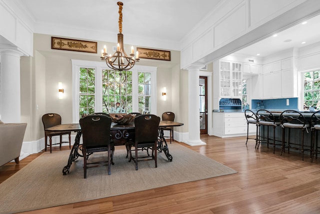 dining space featuring light hardwood / wood-style flooring, decorative columns, and plenty of natural light