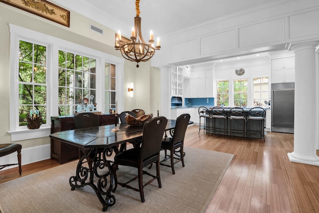 dining area with light hardwood / wood-style flooring, decorative columns, and a healthy amount of sunlight