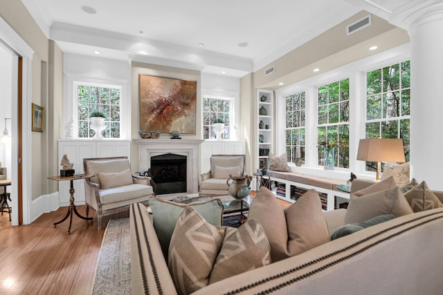 living room featuring light wood-type flooring, ornamental molding, and built in features