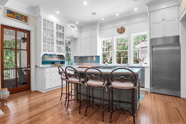 kitchen featuring appliances with stainless steel finishes, ornamental molding, light wood-type flooring, and white cabinets