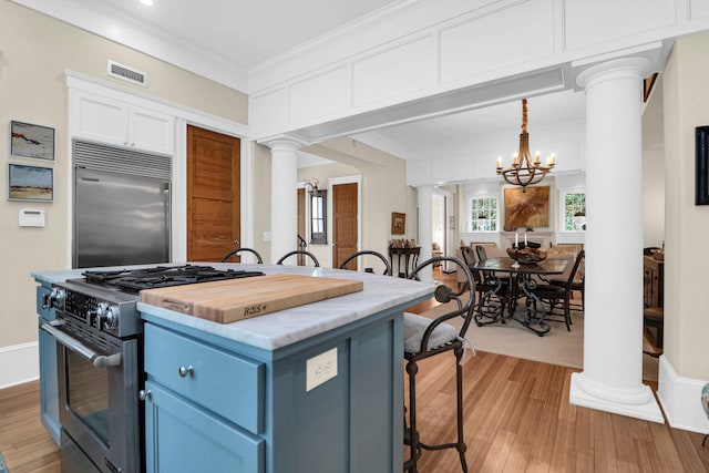 kitchen featuring a chandelier, high end appliances, white cabinets, decorative columns, and blue cabinets