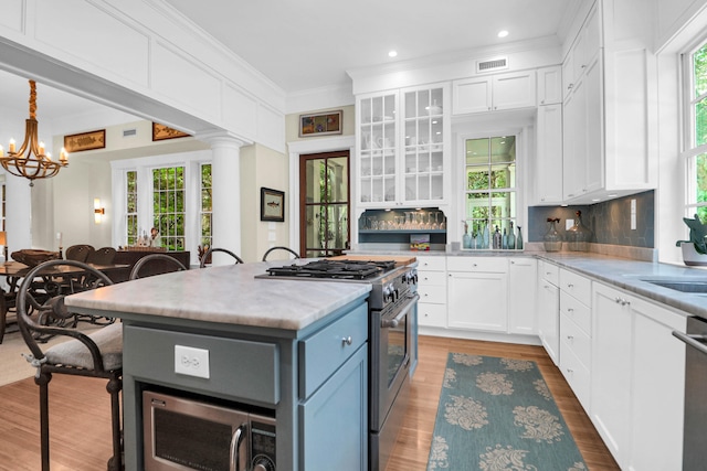 kitchen featuring appliances with stainless steel finishes, a center island, a kitchen bar, and white cabinetry