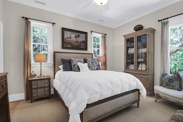 bedroom featuring ceiling fan, light wood-type flooring, and multiple windows