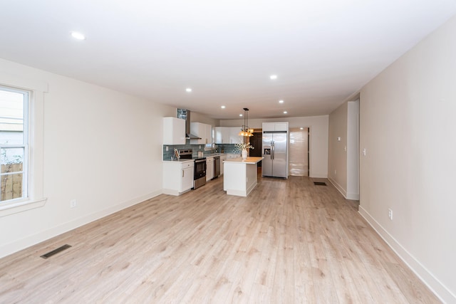 kitchen featuring hanging light fixtures, white cabinetry, a kitchen island, stainless steel appliances, and light hardwood / wood-style flooring