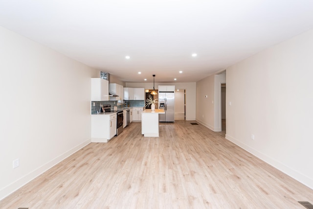 kitchen with a kitchen island, decorative light fixtures, white cabinetry, stainless steel appliances, and light wood-type flooring