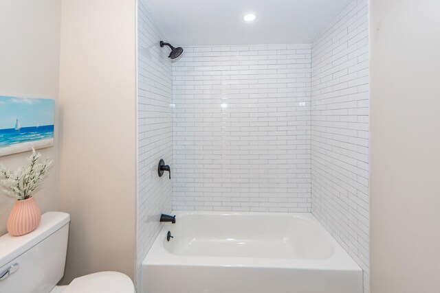 bathroom with toilet and tiled shower / bath