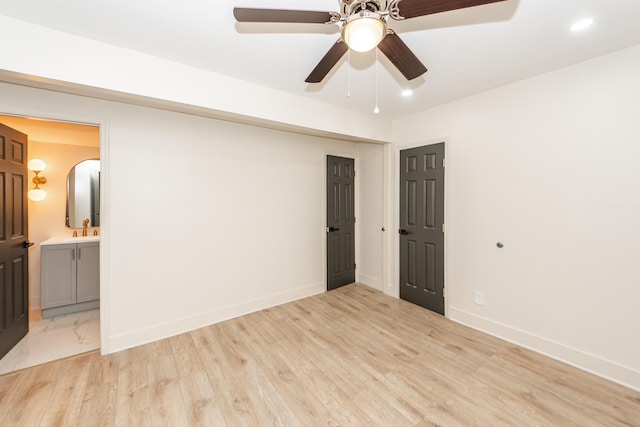 unfurnished bedroom featuring ceiling fan, light wood-type flooring, connected bathroom, and sink