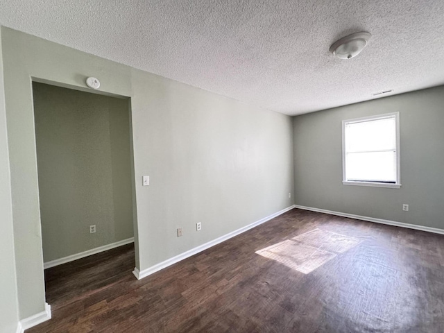 unfurnished room featuring a textured ceiling and dark hardwood / wood-style floors