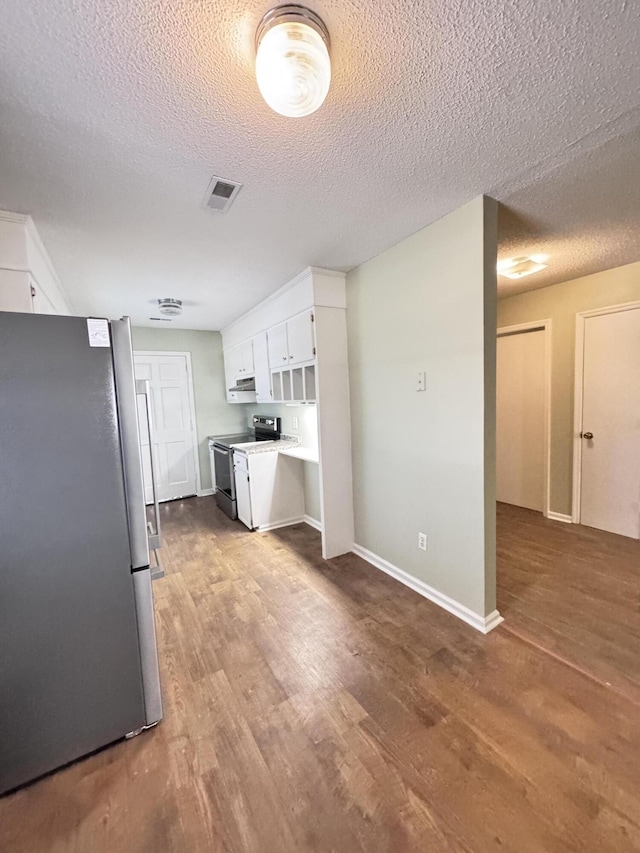 kitchen featuring wood-type flooring, appliances with stainless steel finishes, white cabinetry, and a textured ceiling