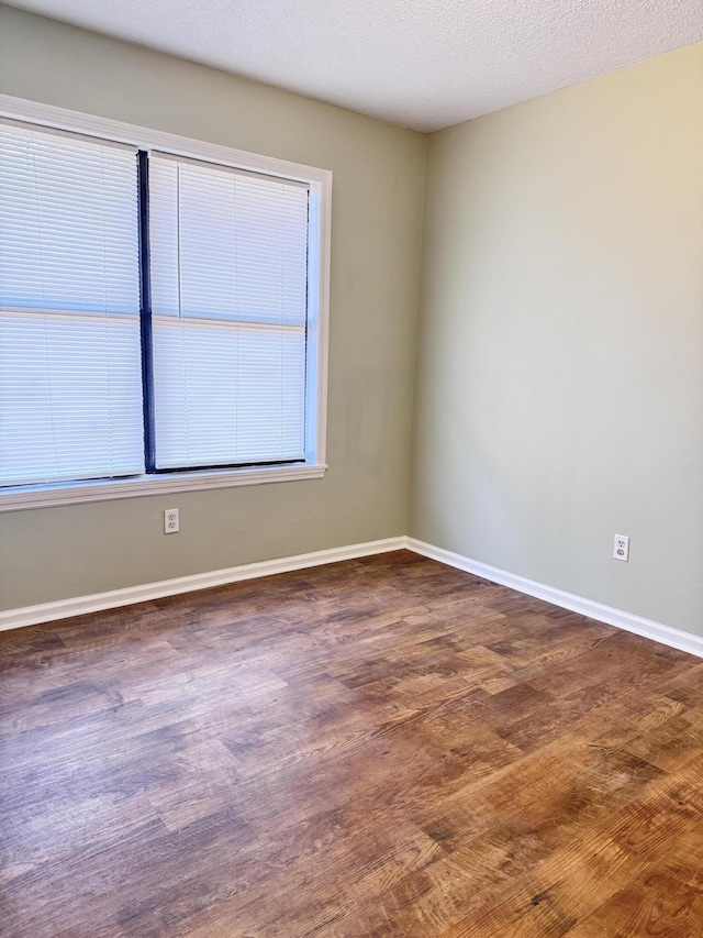 spare room featuring a textured ceiling and dark hardwood / wood-style flooring