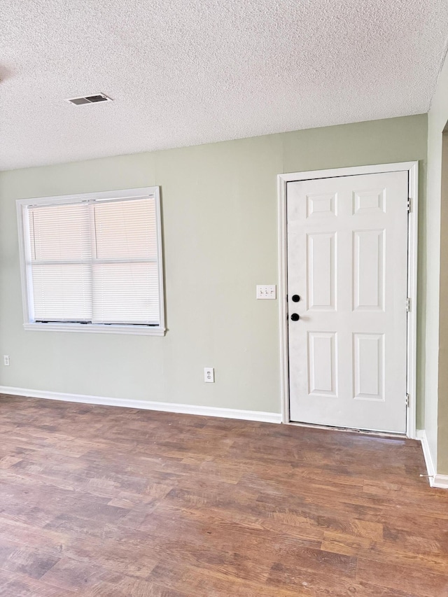 empty room with dark hardwood / wood-style floors and a textured ceiling