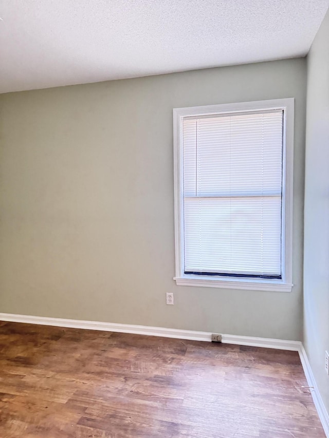 empty room with a textured ceiling and hardwood / wood-style flooring