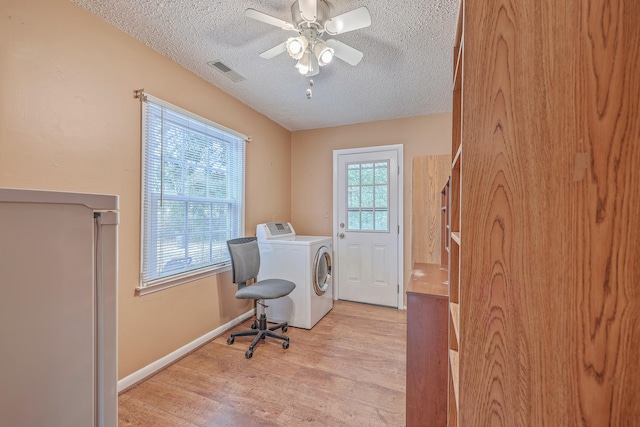 clothes washing area featuring washer / dryer, visible vents, light wood-style flooring, and a textured ceiling