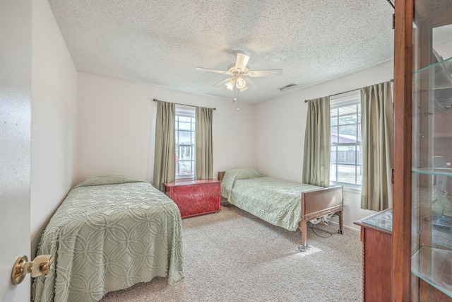 bedroom with carpet, multiple windows, a ceiling fan, and a textured ceiling