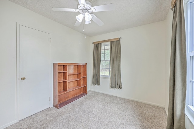 unfurnished bedroom with a ceiling fan, a textured ceiling, and light colored carpet