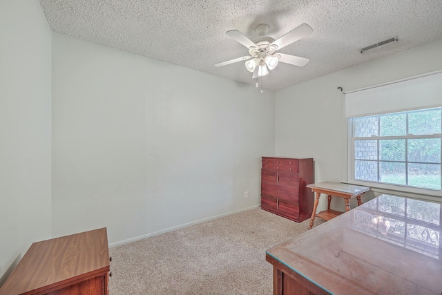 office space featuring a ceiling fan, visible vents, a textured ceiling, and light colored carpet