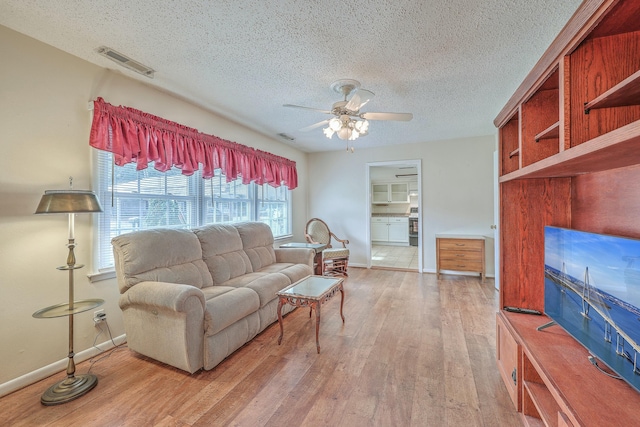 living area featuring baseboards, wood finished floors, visible vents, and a ceiling fan