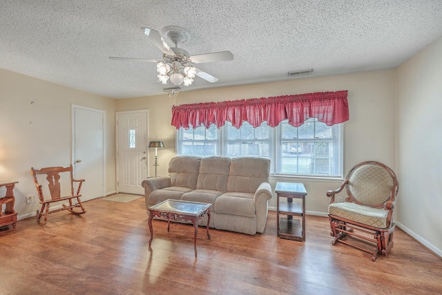 living area featuring visible vents, ceiling fan, baseboards, and wood finished floors