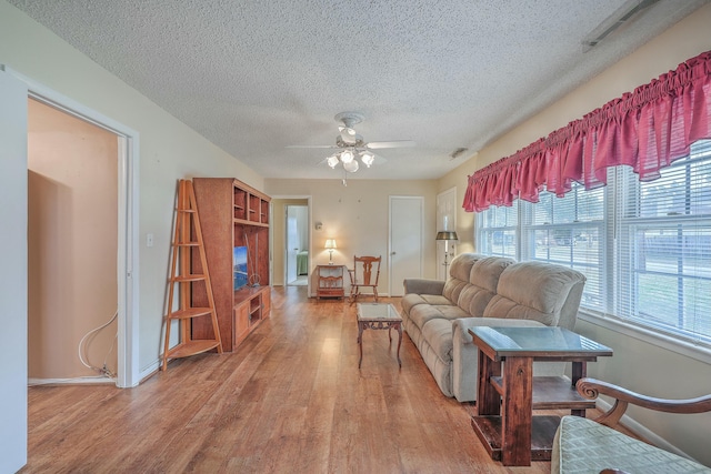 living room featuring baseboards, ceiling fan, visible vents, and wood finished floors