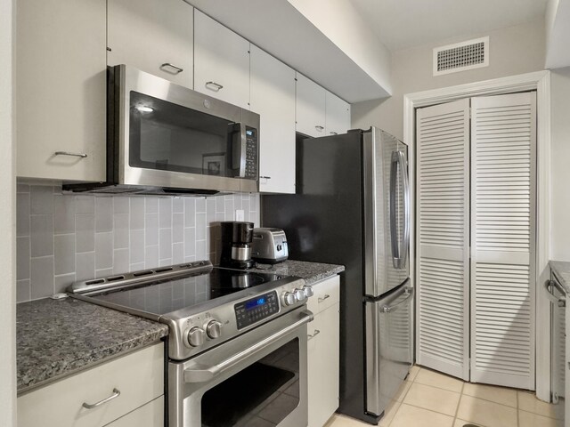 kitchen featuring dark stone counters, tasteful backsplash, white cabinetry, appliances with stainless steel finishes, and sink