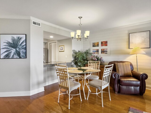 dining room with crown molding, light hardwood / wood-style flooring, and a chandelier