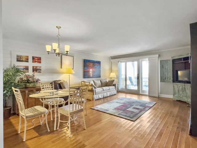 living room featuring light wood-type flooring, crown molding, and a notable chandelier