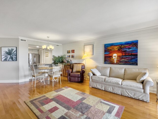 living room featuring light hardwood / wood-style floors, a notable chandelier, and ornamental molding