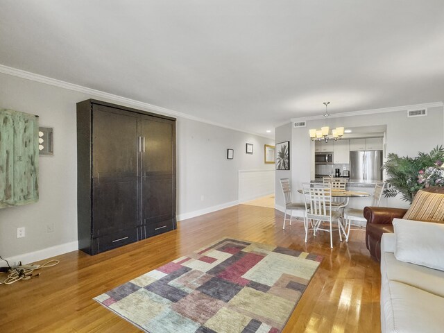 living room featuring light wood-type flooring, a notable chandelier, and ornamental molding